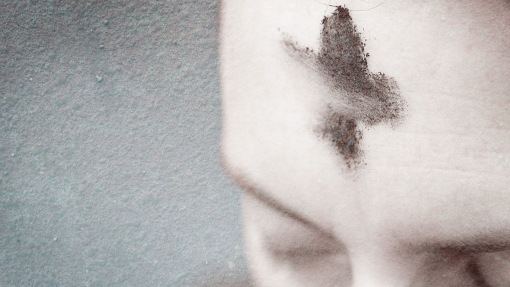 A person's forehead with a cross of ashes on it.